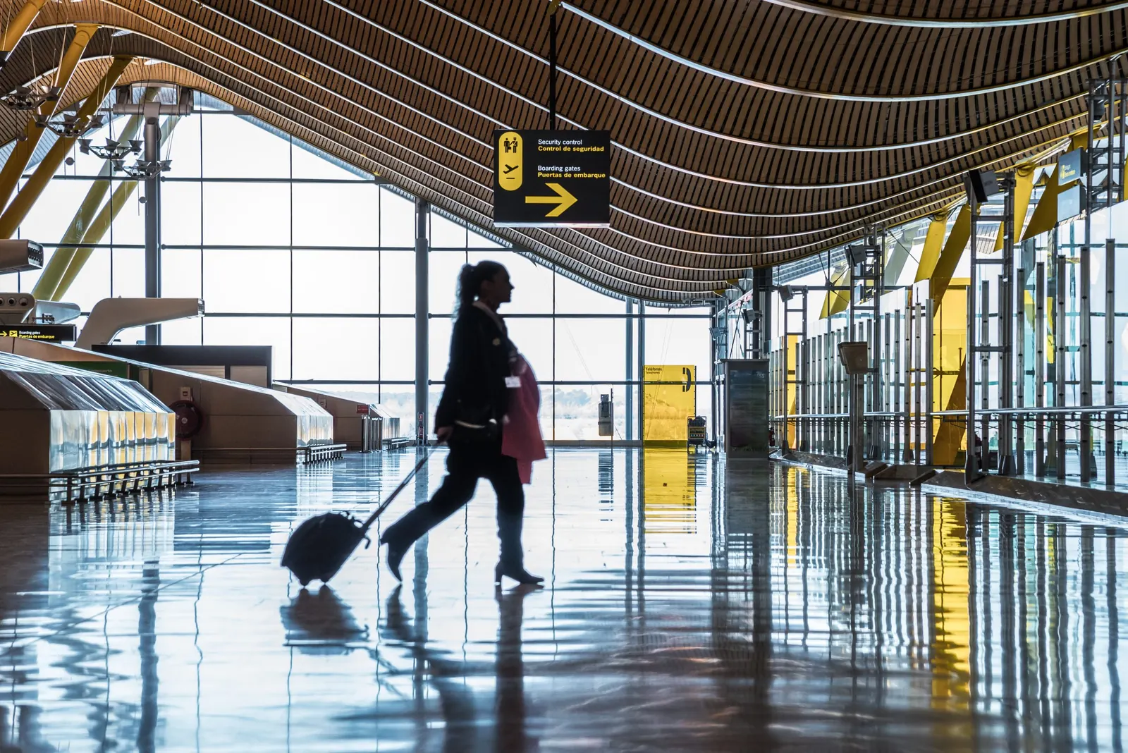 Traveller wheeling a suitcase through a bright airport terminal